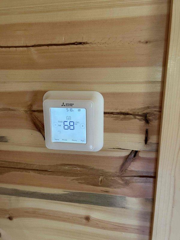 Returned to site to address post-installation issues on multi-zone ductless mini-split system. Installed Mitsubishi Electric wireless thermostats on indoor head units per customer preference and original sales agreement, replacing standard remote controllers. Diagnosed and repaired water leakage on two of three indoor air handlers, restoring units to operational status. Replaced undersized outdoor unit pad with larger concrete pad to properly support condenser stand, ensuring adequate clearance and stability. Secured outdoor unit stand feet to pad for improved structural integrity and code compliance. Verified all indoor units operating without leakage, thermostat communication functioning properly, and outdoor unit securely mounted on appropriately sized pad. System tested and confirmed operational.