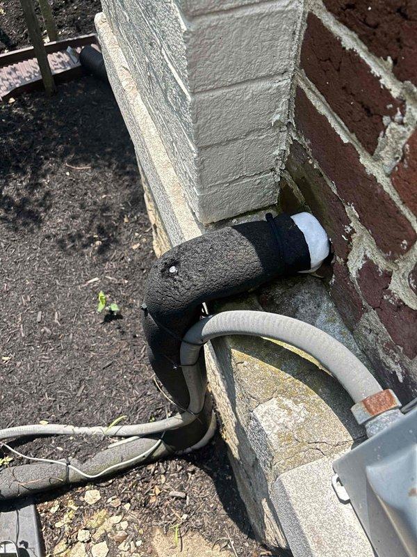 Responded to no cooling call on 15-year-old electric air conditioning system serving upstairs zone. Upon arrival, found upstairs thermostat blank with no power and system blowing warm air. Indoor unit located in upstairs bathroom, accessed via attic stairs.

Initial inspection revealed frozen evaporator coil on air handler. System was shut down to allow complete thaw before further diagnostics could be performed. Inspected outdoor condensing unit and noted electrical contactor showing signs of age with discolored terminals and weathered housing. Multiple wire connections at contactor terminals displayed normal wear consistent with system age. Outdoor refrigerant lines protected with foam insulation showed weathering and some deterioration at foundation penetration point.

Documented equipment condition with photos showing contactor assembly, wire connections, and exterior refrigerant line routing. System requires return visit after thaw cycle completes to diagnose root cause of freezin