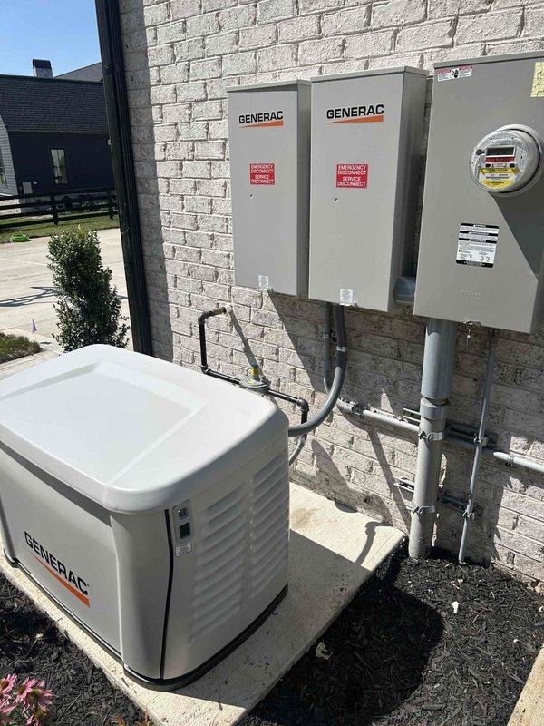 Installed 26KW Generac backup generator and connected to two existing transfer switches mounted on exterior brick wall. Ran electrical conduit from generator unit through transfer switches to meter assembly, with all connections properly secured and labeled. Customer provided gas supply components for the installation, which were integrated into the system per manufacturer specifications.