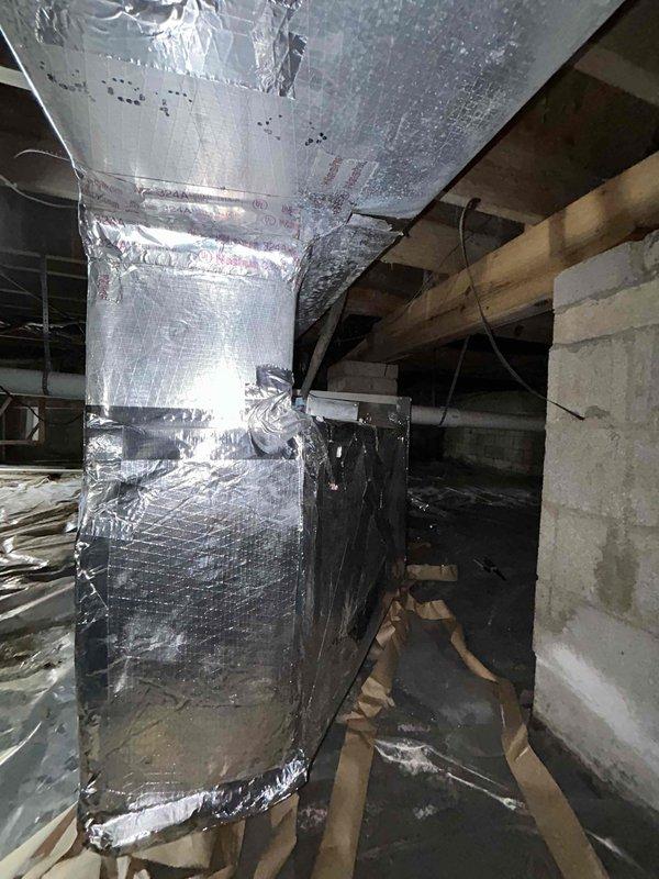 Completed reconstruction of supply plenum ductwork using duct board material in basement mechanical space. Removed existing metal supply plenum and replaced with properly insulated duct board construction, secured with metallic tape at all seams and joints to ensure proper air seal and thermal efficiency. Installation completed in crawl space area with new reflective insulation wrapping to prevent heat loss and condensation issues.
