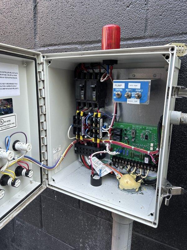 Responded to service call for dual waste pump system located in exterior fenced area behind garage structure. Conducted inspection of pump basin and control panel to assess reported bearing failure on primary unit. Confirmed one pump inoperative due to failed bearings, while secondary pump operational. Documented existing system configuration including float switches, control panel with circuit breakers, contactors, and pump control module. Photographed basin interior showing water level, pump components, float mechanisms, and diamond-plate access cover. Inspected electrical control panel revealing dual pump control system with automated switching capability. Noted system age and potential warranty coverage on equipment. Prepared comprehensive estimate for replacement of both waste pumps to ensure continued reliable operation of wastewater removal system.