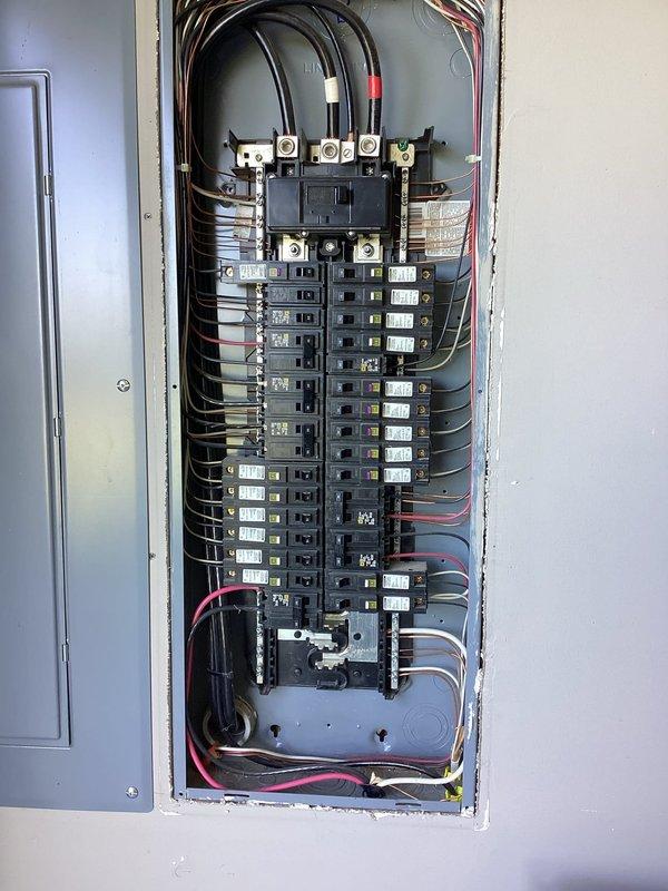 Conducted comprehensive electrical assessment for backup generator installation at residential property. Documented existing 200-amp main service panel configuration, including current circuit breaker layout, wire routing, and available capacity for generator interlock or transfer switch integration. Photographed panel interior showing dual-column breaker arrangement, main disconnect assembly with copper bus connections, and existing circuit directory to determine optimal connection point for emergency power system. Evaluated panel condition, verified proper wire sizing and terminations, and assessed structural requirements for generator tie-in equipment installation.