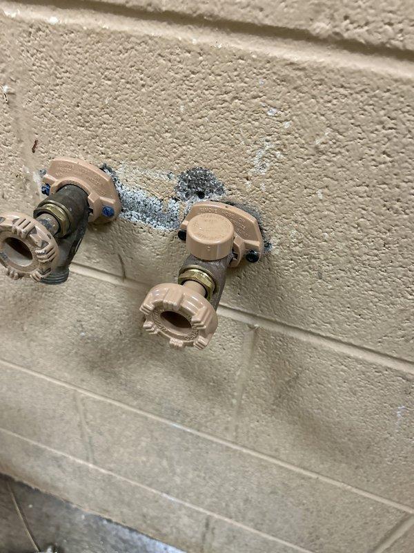 Responded to service call for multiple plumbing issues including a noisy toilet in the half bath, unsecured hydrant at barn wall, and leak under master bathroom. Inspected vintage high-tank toilet system with overhead wooden tank and pull-chain flush mechanism; diagnosed intermittent running noise and assessed flush valve and fill valve operation. Examined water supply shutoff valves showing corrosion and oxidation on copper piping with evidence of moisture damage and water staining on surrounding wall surface, indicating active or previous leak condition. Secured hydrant mounting at barn location and documented all findings with photographic evidence for repair recommendations.