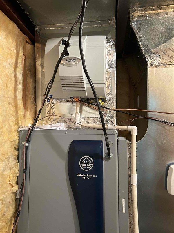 Completed residential geothermal system installation featuring a WaterFurnace 3.5-ton 5 Series packaged unit (model W5AV042BD1A12CTR2B00) configured as vertical with right return. Installed two-pump flow center (FC2-FPT), 10kW heat kit, WaterFurnace digital thermostat (TPCC32U03WWFI), hot water de-superheater, UV light system, and condensate pump. 

Return visit performed to finalize installation work. Replaced 16x20x4" air filter on upstairs air handler. Modified supply transition by replacing front face and repositioned humidifier mounting as high as possible to maintain clearance from heat strips. Re-worked humidifier drain line for proper drainage. Installed new saddle tap for humidifier water supply line. Completed electrical connections for humidifier and humidifier control wiring. 

Piped in de-superheater for domestic hot water heating integration. Insulated all geothermal loop lines to prevent condensation and maintain system efficiency. Installed return drop ductwork. System 