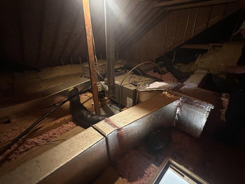 Conducted attic assessment for ventilation and insulation improvements. Evaluated existing attic space with exposed rafters, wooden planking, and HVAC ductwork with reflective insulation, noting minimal pink fiberglass insulation coverage on attic floor and exposed joists. Inspected roof structure including trusses, beams, and OSB sheathing to determine feasibility for gable vent installation and prepared estimate for proper attic ventilation system and blown insulation installation to improve indoor air quality and energy efficiency.