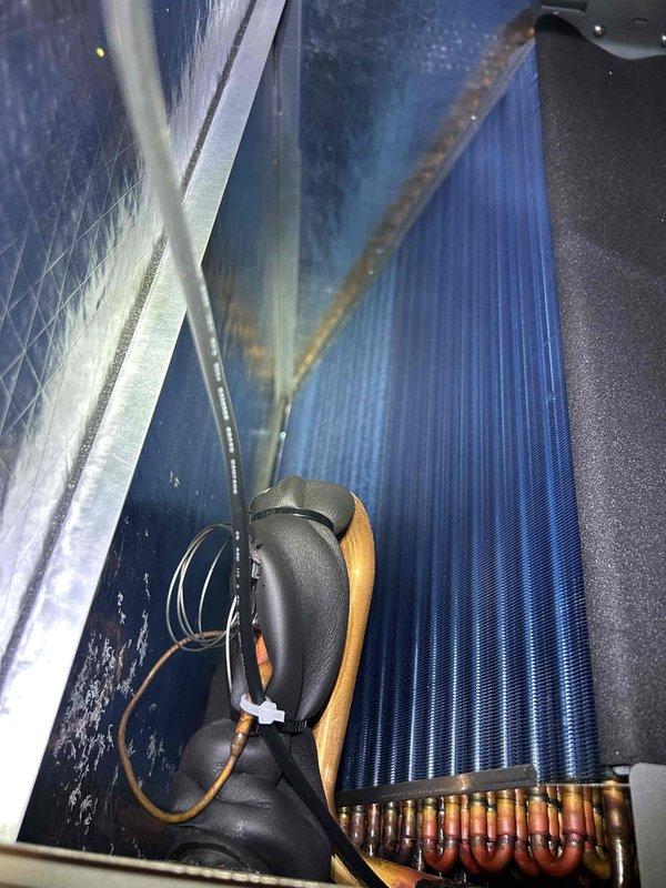 Completed Care Plan tune-up on heat pump and air handler system located in closet with filter grills inside residence. Inspected evaporator coil showing blue fins with visible rust-colored debris accumulation along top edge and confirmed copper refrigerant line connections with minor oxidation present. Measured and documented airflow at interior register reading 54.65, verified system operation, and noted customer provides their own filters for ongoing maintenance.