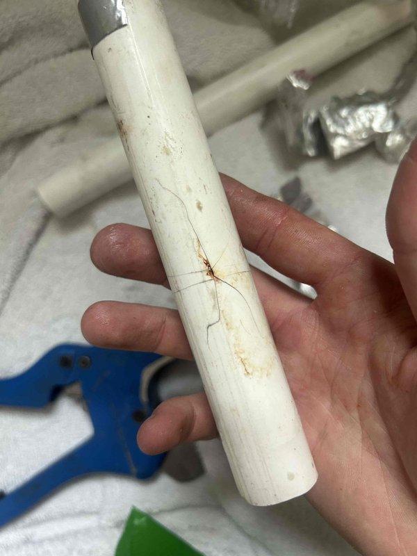 Responded to customer report of condensate line leak causing interior water damage. Upon arrival, found drywall had been removed by homeowner, exposing vertical PVC condensate drain pipe with visible crack and deterioration. Inspected damaged pipe section and confirmed active leak from fractured condensate line. Documented condition with photographs showing cracked PVC pipe with discoloration and linear defect. Removed damaged section of condensate drain pipe and assessed surrounding plumbing connections. Discussed repair options with customer including full pipe replacement versus sectional repair to restore proper drainage function and prevent further water damage to interior walls.