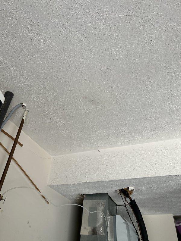 Responded to intermittent water leak in main upstairs bathroom. Upon inspection, identified water damage and staining on ceiling below bathroom, with visible tan-colored patches and potential mold growth indicating ongoing moisture intrusion. Investigated leak source, documented damage extent through photography, and assessed affected areas including ceiling texture and surrounding storage space. Recommended further investigation of bathroom plumbing fixtures and drainage systems to identify intermittent leak source and prevent additional water damage.