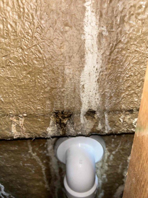 Responded to emergency water leak originating from second-story bathroom with damage visible in closet below. Upon investigation, accessed wall cavity and inspected plumbing system serving tub/shower area. Located source of water intrusion at copper supply line connection with compromised fitting. Repaired leaking connection using brass compression fittings and secured copper piping with proper mounting brackets. Applied spray foam insulation around plumbing penetrations to seal cavity and prevent future moisture migration. Documented water-damaged drywall in lower closet showing bowing and saturation requiring replacement by property owner or contractor.
