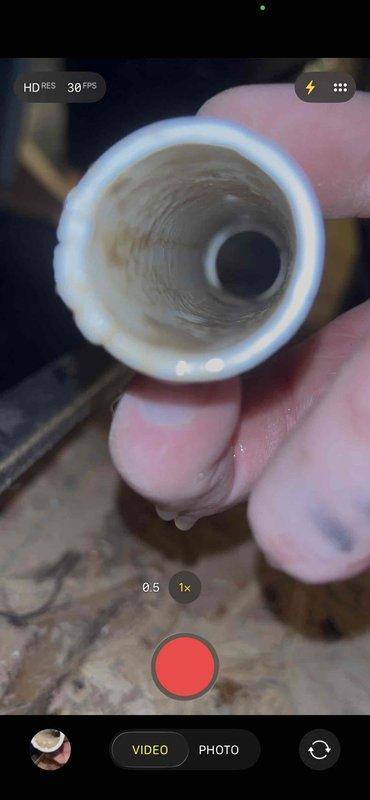 Responded to no cooling call with blank thermostat on 11-year-old electric AC system with indoor unit located in attic. Upon inspection, discovered condensate drain line completely blocked with biological growth and sediment buildup, causing safety float switch to trip and shut down system. Cleared blockage from drain line, flushed system, verified proper drainage, and restored power to unit—thermostat display returned and system resumed normal operation.