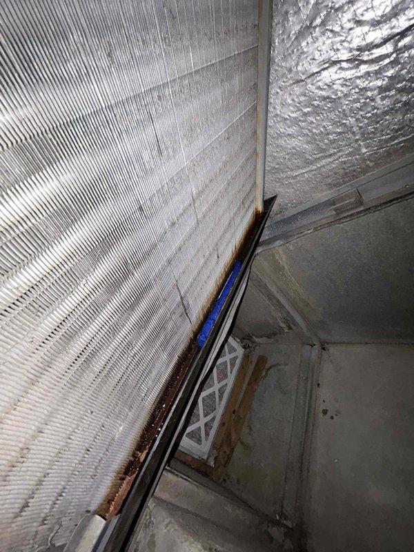 # HVAC Service Report - Water Leak Repair

Responded to service call for active water leak from air conditioning system. Upon arrival, confirmed water leaking onto floor from 13-year-old AC unit that was otherwise cooling properly.

Conducted thorough inspection of the condensate drainage system and identified failed drain fitting as the source of the leak. The compromised fitting was allowing condensate water to bypass the drain line and discharge directly onto the floor. Removed the defective black threaded metal and white plastic compression fitting component.

Installed new drain fitting to restore proper condensate drainage. Verified all connections were secure and leak-free. Tested system operation to confirm water was draining correctly through the condensate line without any further leakage. Inspected surrounding area for any water damage, noting moisture staining on insulation material at floor level in the unit location.

System restored to normal operation with proper conden