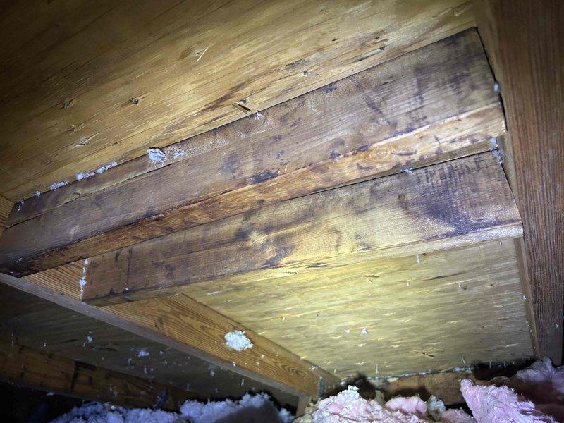 Responded to concerns regarding potential condensate leak from attic-mounted air handler causing bathroom ceiling damage. Inspected 15-year-old Trane unit (Model# 4TWB3024D1000AA, Serial# 14132TXN4F) with history of drain pan issues. Performed thorough examination of air handler, condensate drain pan, primary and secondary drain lines, and surrounding attic structure for active leaks, moisture accumulation, and proper drainage. Documented attic conditions including wooden framing with visible water staining and discoloration on structural members, indicating previous moisture intrusion. Examined flexible ductwork and insulated plenum connections for condensation issues. Assessed drain pan alignment and condensate removal system functionality to determine cause of overflow affecting ceiling below and potential correlation with bathroom exhaust fan electrical problems.