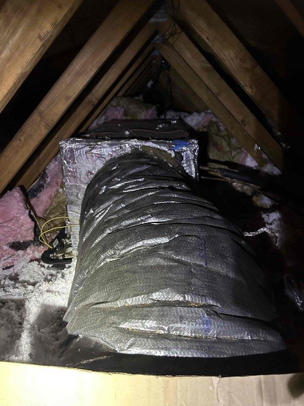 Responded to concerns regarding potential condensate leak from attic-mounted air handler causing bathroom ceiling damage. Inspected 15-year-old Trane unit (Model# 4TWB3024D1000AA, Serial# 14132TXN4F) with history of drain pan issues. Performed thorough examination of air handler, condensate drain pan, primary and secondary drain lines, and surrounding attic structure for active leaks, moisture accumulation, and proper drainage. Documented attic conditions including wooden framing with visible water staining and discoloration on structural members, indicating previous moisture intrusion. Examined flexible ductwork and insulated plenum connections for condensation issues. Assessed drain pan alignment and condensate removal system functionality to determine cause of overflow affecting ceiling below and potential correlation with bathroom exhaust fan electrical problems.
