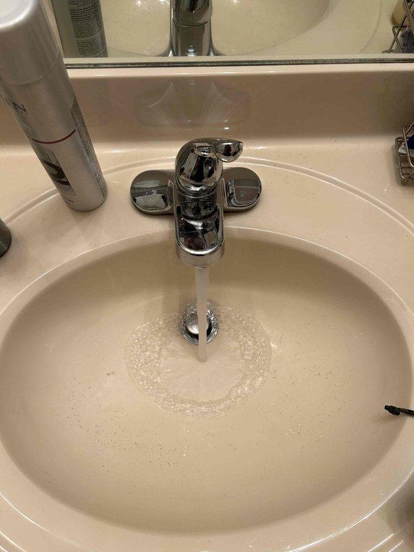 Completed comprehensive 65-point plumbing inspection of residential property. Inspected bathroom vanity sink and faucet assembly, verifying proper water flow and drainage operation. Examined under-sink plumbing components including chrome pop-up drain assembly, white PVC P-trap configuration with coupling nuts, and flexible supply lines for leaks or deterioration. Tested faucet functionality with single-handle chrome fixture, confirming adequate water pressure and temperature control operation. All visible plumbing fixtures and connections found to be in serviceable condition with no active leaks detected at time of inspection.