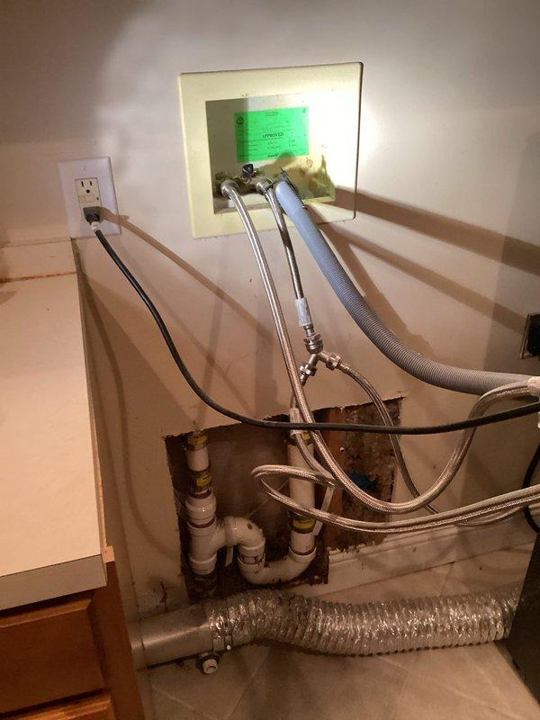 Responded to water leak originating from washing machine supply lines affecting kitchen area. Upon arrival, accessed plumbing cavity through wall to identify source of leak. Investigation revealed compromised flexible supply line connections at washer hookup location. Removed wall access panel to expose mechanical chase containing water supply lines, drain system, and associated plumbing components. 

Inspection identified active leak from deteriorated braided stainless steel supply hose connections. Water intrusion had caused visible staining and discoloration on PVC drain piping within wall cavity. Shut off water supply at isolation valves to prevent further water damage. Removed failed supply lines and assessed condition of connection points and shutoff valves. 

Installed new braided stainless steel washing machine supply hoses with proper torque specifications at both fixture and valve connections. Tested all connections under full pressure to verify leak elimination. Inspected su