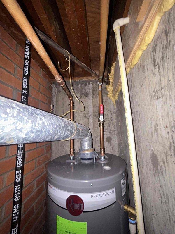 # Plumbing Inspection Summary

Completed routine plumbing preventative service agreement inspection of residential property. Performed comprehensive visual assessment of accessible plumbing systems and fixtures per recurring maintenance plan protocol.

## Water Heater Inspection

Inspected Rheem Professional water heater unit located in basement utility area. Verified proper installation positioning and clearances. Examined all visible connections including copper supply lines, PVC venting system, and pressure relief valve assembly. Noted red-handled temperature and pressure relief valve present and properly installed. Checked for signs of corrosion, leakage, or deterioration on tank exterior and all pipe connections. Observed insulation wrapping on hot water distribution line. Unit appeared to be functioning within normal parameters with no active leaks or safety concerns identified at time of inspection.

## Under-Sink Plumbing Assessment

Inspected bathroom sink drain assembly and w
