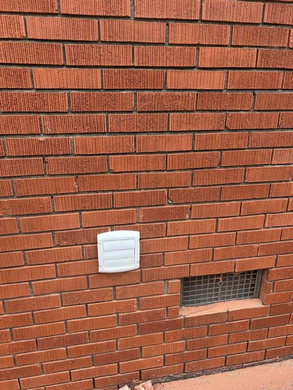 Installed complete dryer vent system from interior basement location to exterior wall termination. Routed 4-inch metal ductwork through crawl space using five sections of rigid pipe and four 90-degree elbows to navigate around floor joists and existing utilities. Secured all connections with foil tape to ensure airtight seal and proper airflow. Terminated vent through red brick exterior wall with black louvered vent cap for weather protection and proper exhaust discharge.