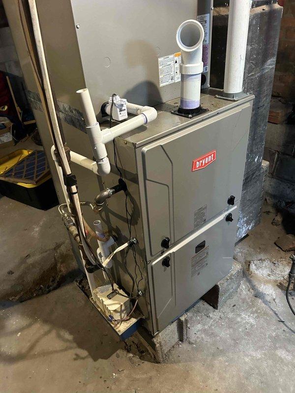 Responded to no cooling complaint on 2-year-old electric AC system reporting warm air discharge and unusual noise. Upon arrival, verified thermostat set to cooling mode at 74°F. Performed diagnostic inspection of Bryant furnace/air handler and outdoor condensing unit. Identified abnormal operational sounds requiring further investigation of blower motor assembly and compressor function. Documented system configuration and current operating conditions with photographic evidence for service records.
