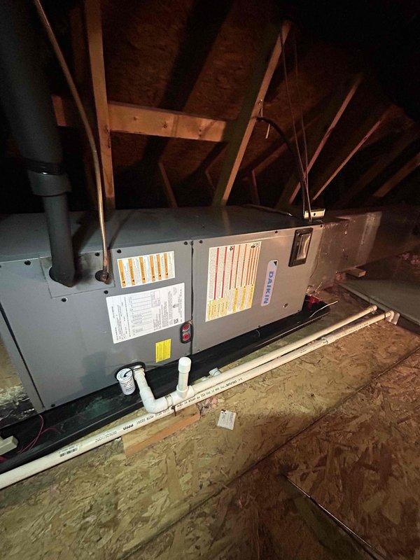 # HVAC Cooling System Repair - Dual Zone System Failure

Responded to no cooling condition affecting both zones of a dual-system residential HVAC installation with a 9-year-old air conditioning system. Customer reported the bottom unit failed approximately one month prior, followed by the top unit ceasing operation several days ago, resulting in complete loss of cooling to the residence.

Upon arrival, accessed attic-mounted air handler units to diagnose the system failures. Performed visual inspection of both HVAC units, including examination of electrical connections, condensate drainage systems, and ductwork integrity. Evaluated the gray metal air handler units mounted horizontally in the attic space, checking all visible components including warning labels, specification plates, and safety systems.

Inspected black cylindrical vent piping and white PVC condensate drain lines for proper operation and potential blockages. Verified drain line routing, joints, and connectors to ensure 