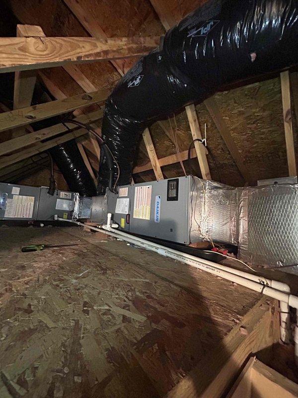 # HVAC Cooling System Repair - Dual Zone System Failure

Responded to no cooling condition affecting both zones of a dual-system residential HVAC installation with a 9-year-old air conditioning system. Customer reported the bottom unit failed approximately one month prior, followed by the top unit ceasing operation several days ago, resulting in complete loss of cooling to the residence.

Upon arrival, accessed attic-mounted air handler units to diagnose the system failures. Performed visual inspection of both HVAC units, including examination of electrical connections, condensate drainage systems, and ductwork integrity. Evaluated the gray metal air handler units mounted horizontally in the attic space, checking all visible components including warning labels, specification plates, and safety systems.

Inspected black cylindrical vent piping and white PVC condensate drain lines for proper operation and potential blockages. Verified drain line routing, joints, and connectors to ensure 