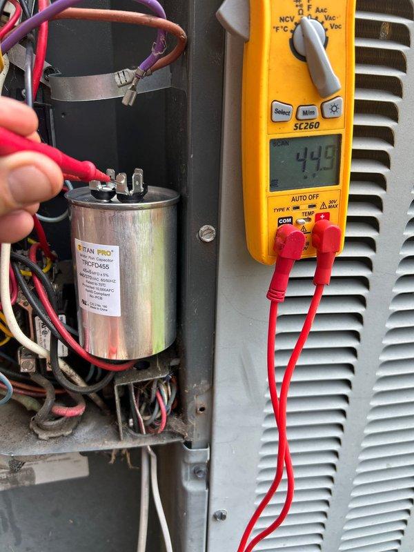 Responded to no cooling complaint on 10-year-old electric HVAC system with air circulation but no cooling capability. Performed electrical diagnostics on outdoor condensing unit using clamp meter and multimeter. Testing revealed failed run capacitor with readings outside acceptable parameters. Measured existing TITAN PRO 370 VAC capacitor (model TRC-FD45S) showing improper capacitance values of 10.9 and 44.5 microfarads, indicating capacitor failure preventing compressor from operating properly. Verified all electrical connections at capacitor terminals and confirmed compressor circuit integrity. Replaced defective dual run capacitor with new unit matching original specifications. Restored power to system and verified proper compressor startup and operation. Confirmed adequate cooling air temperature at supply registers and normal system amperage draw. System operating within manufacturer specifications upon departure.