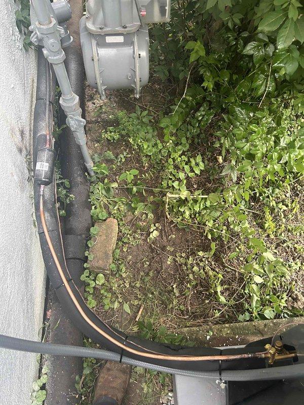 Completed full residential HVAC system replacement including installation of Trane 100K BTU two-stage 97% efficiency gas furnace (model S9V2C100U5VSBB), Trane 5-ton 14.3 SEER2 air conditioning unit (model 5TTR4060A1000A), matching evaporator coil (model 5TXCCOO7AS3HCA), and digital thermostat. Removed existing equipment and disposed of properly, then installed bottom base box to ensure proper airflow for the AC unit. Removed old humidifier and patched penetration hole in ductwork. Installed outdoor condenser unit on new concrete pad with gravel packed between and around pavers to eliminate hollow spots and ensure stable, level support. Connected refrigerant lines with proper insulation, installed electrical whip kit and disconnect box at outdoor unit, and ran electrical conduit along exterior wall. Installed flexible gas line connector with gas shut-off switch, connected to flue piping with proper transitions, and added flame roll-out protection. Installed electrical shut-off switch, s