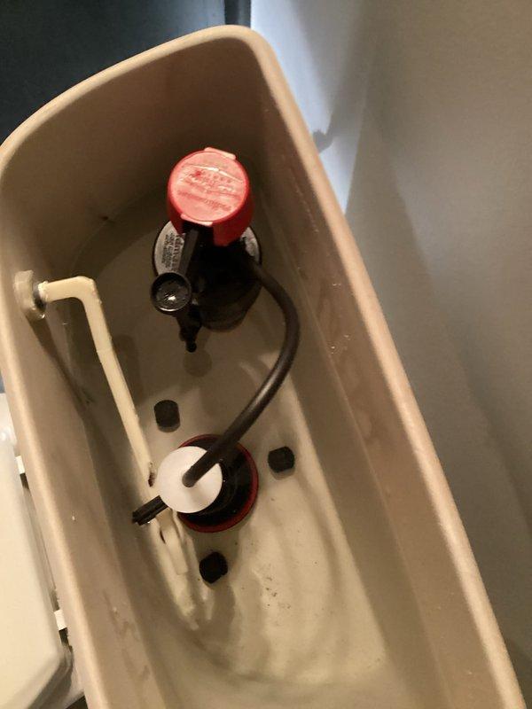 Completed toilet tank rebuild service. Removed and replaced all internal flush mechanisms including fill valve assembly with red-capped actuator, flapper valve with rubber seal, and overflow tube connections. Installed new components, adjusted water level settings, tested flush operation for proper function, and verified tank refill cycle operating within normal parameters.