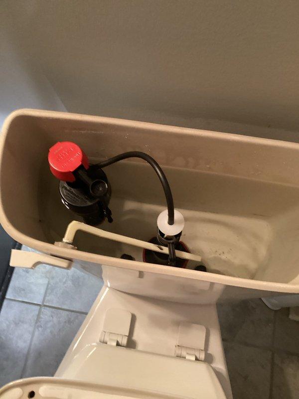 Completed toilet tank rebuild service. Removed and replaced all internal flush mechanisms including fill valve assembly with red-capped actuator, flapper valve with rubber seal, and overflow tube connections. Installed new components, adjusted water level settings, tested flush operation for proper function, and verified tank refill cycle operating within normal parameters.
