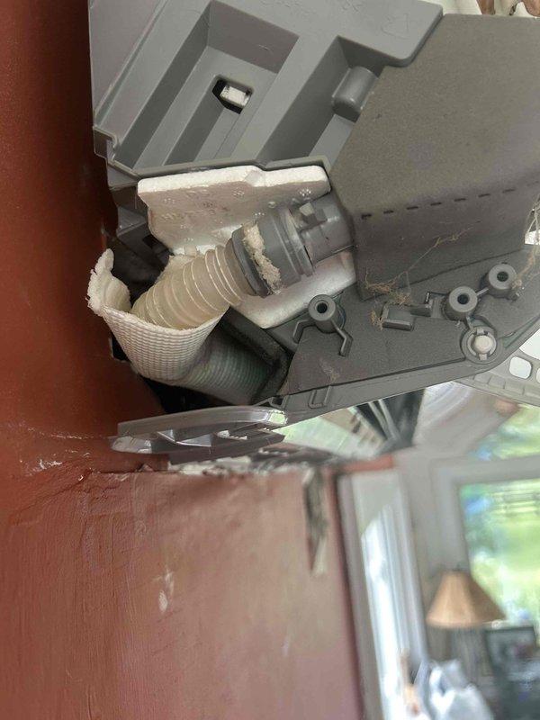 Responded to water leak complaint at indoor HVAC unit in sunroom that had been leaking for several days. Unit was off upon arrival. Performed diagnostic inspection and discovered condensate drain line issue with visible mineral deposits and buildup at drain connection point. Inspected attic space and ductwork, finding pink fiberglass insulation with signs of water damage and discoloration around affected area. Documented conditions with photographs showing deteriorated drain fitting with crusty residue accumulation and water-damaged insulation materials. Identified source of water intrusion coming from behind unit due to compromised condensate drainage system.