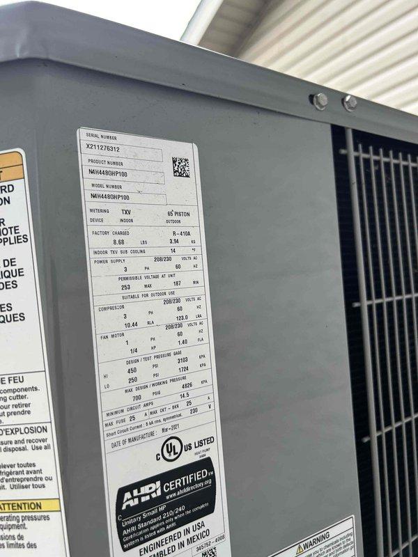 Responded to commercial property no-cooling complaint with interior temperature at 87°F. Inspected 9-year-old Goodman N4H448GBP100 condenser unit and found system operational with proper refrigerant charge and compressor function. Verified unit specifications, electrical connections, and heat exchanger components showed no visible defects or refrigerant leaks, with all safety labels and certifications intact.
