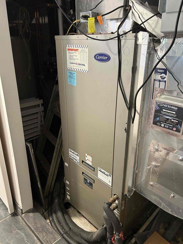 Responded to no cooling complaint on 10-year-old geothermal system affecting entire home. Upon arrival, customer reported recurring issue with same component requiring repeated replacement. Performed diagnostic testing on Carrier air handler unit, including temperature measurements that revealed abnormal readings of 32.3°F at evaporator coil, indicating potential refrigerant flow or control issues. Inspected electrical connections, ductwork, and associated components in mechanical room. Documented system condition with photos showing air handler, electrical panel, ductwork connections, and temperature readings. Identified failing component consistent with customer's reported history of repeated failures on this particular part. Recommended replacement of defective component to restore proper cooling operation and discussed pattern of recurring failures with customer for long-term resolution consideration.
