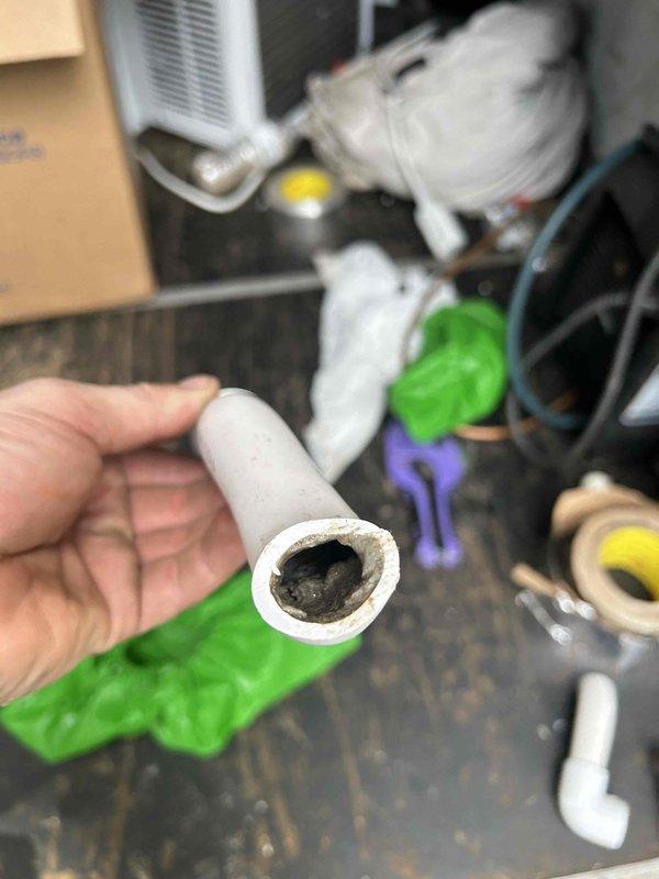 # HVAC Service Completed

Responded to no-cooling complaint on 6-year-old Bryant heat pump system located in attic. Unit experiencing complete shutdown with issue persisting through two prior service visits. 

Upon arrival, performed comprehensive system diagnostics. Accessed attic-mounted air handler and inspected all major components. Evaluated ductwork system, noting flexible duct runs throughout attic insulation. Examined condensate drain line and discovered complete blockage causing primary drain pan to fill, triggering float switch safety shutdown. 

Removed and disassembled condensate drain line section, revealing significant algae and debris accumulation restricting water flow. Cleared blockage from drain line using appropriate tools and cleaning methods. Flushed entire condensate system to ensure proper drainage. Reinstalled drain components with proper insulation. Verified float switch operation and reset safety controls.

Tested system operation through complete cooling cycl