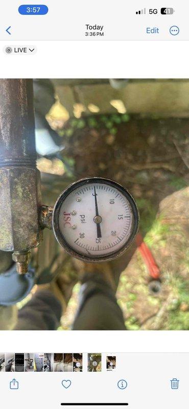 Responded to vacant property for gas leak pressure test following previous technician's assessment. Connected pressure gauge to exterior gas line system to conduct pressurization test on weathered piping infrastructure showing significant age and corrosion. Performed pressure testing procedures on gas distribution system to identify potential leak points, with gauge monitoring maintaining zero PSI reading during inspection. Documented condition of aging metal pipes, corroded fittings, and deteriorated white-painted elbow joints requiring evaluation for system integrity and safety compliance.