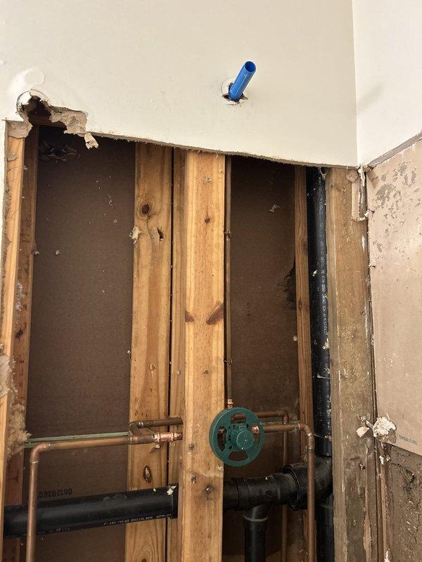Responded to priority service call to remove existing shower fixtures in preparation for scheduled retiling work. Accessed shower valve assembly through wall cavity, disconnected and removed showerhead, trim ring, and valve handle components. Exposed plumbing infrastructure included copper supply lines and Webstone valve assembly with shutoff capability. All fixtures successfully removed to allow tile contractor access to wall surfaces while maintaining system integrity and water supply control for continued tub/shower use until renovation completion.