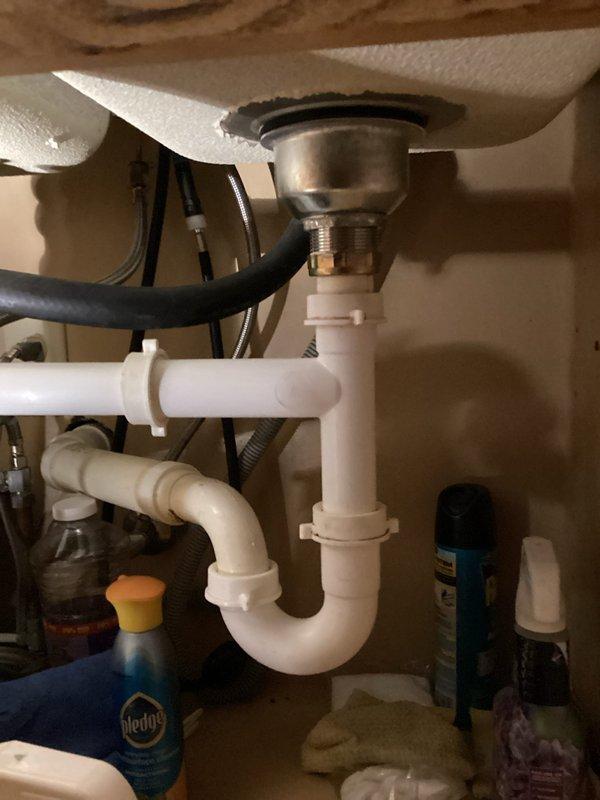 Responded to kitchen sink drain leak that began several days prior. Upon arrival, provided 30-minute advance notice as requested. Accessed cabinet beneath kitchen sink and inspected white PVC P-trap assembly and connections. Identified leak source at drain pipe junction under sink basin. Verified leak was isolated to kitchen plumbing only with no issues affecting other household fixtures.

Examined metallic sink drain basket connection to P-trap assembly and checked all compression fittings and slip joints for proper seal. Inspected black rubber dishwasher or disposal connection hose for potential contribution to leak. Tightened loose slip nut connections on P-trap where leakage was occurring. Verified all PVC fittings were properly seated and compression washers were intact.

Cleared under-sink cabinet area of cleaning supplies and household items to ensure proper access to plumbing components. Tested drain system by running water through sink and monitoring all connections for contin