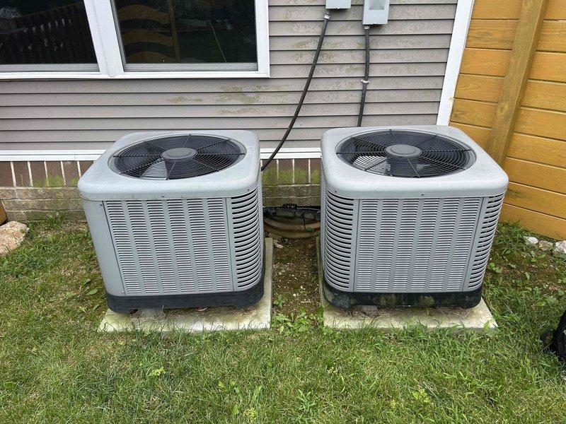Responded to service call for dual heat pump system with both outdoor units producing excessive noise. Upon arrival, performed diagnostic assessment of both 9-year-old heat pump units installed on exterior concrete pads. Conducted operational testing, inspected refrigerant lines, electrical connections, and compressor components on each unit. Evaluated previous repair history noting prior refrigerant recharge and component replacement approximately 18 months ago. Identified noise source through systematic component analysis including fan motor assemblies, compressor operation, and mounting hardware. Verified system pressures and operational parameters on both units to ensure proper cooling performance despite noise concerns. Documented equipment condition with photographic evidence showing dual outdoor condenser configuration and related system components.