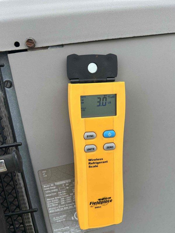Responded to report of steady water drip from first-floor indoor unit that occurred overnight, with system shut down to prevent further leakage. Inspected rooftop HVAC equipment including condenser unit and refrigerant line set connections. Performed diagnostic assessment and weighed refrigerant charge using calibrated scale, measuring 3.0 pounds to verify system levels and identify potential causes of condensate overflow or drain line blockage.