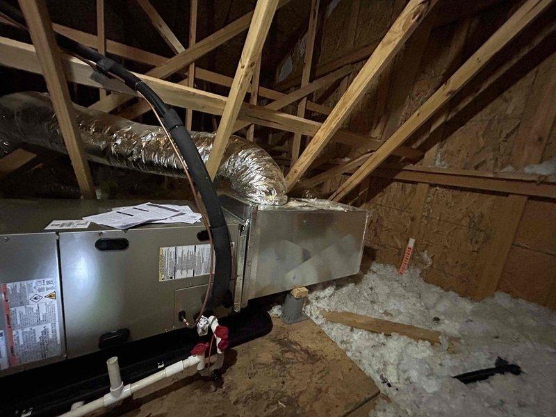 Completed full residential HVAC system installation in attic space accessible via garage pulldown access. Installed Bryant 2.5 ton 14.3 SEER2 heat pump system (model GH5SAN53000A) with matching Bryant air handler (model FJ5ANXB30L00) positioned in attic and Bryant 10 KW electric heat kit (model TU-EC-10BKB) for supplemental heating. Integrated system with existing thermostat to maintain customer's preferred controls. Installed outdoor unit pad with snow legs for equipment support and elevation, electrical whip kit, and electrical disconnect box for code-compliant power supply. Ran and insulated refrigerant lines between outdoor heat pump and attic-mounted air handler, installed refrigerant line filter for system protection. Removed and disposed of existing HVAC equipment per industry standards. Charged system with R454B refrigerant and performed complete startup procedures. Verified proper system operation with manifold gauge readings showing balanced pressures at 36.74 PSIG and 36.72 