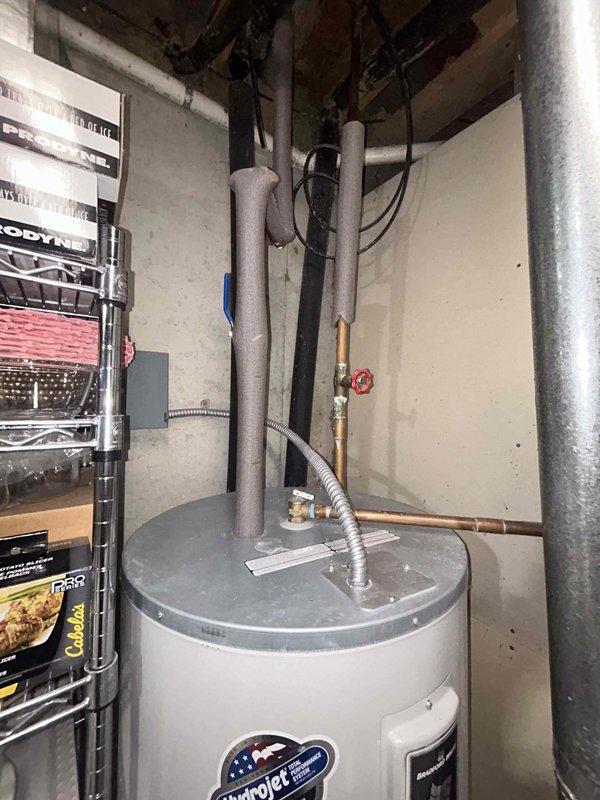 Conducted comprehensive assessment of existing 80-gallon Bradford White tank-style water heater installed in basement mechanical room serving geothermal heating system. Evaluated current unit condition, plumbing connections including PEX supply lines with brass manifold assembly, shut-off valves, and flexible connectors. Documented installation configuration with copper and insulated piping at top connections, pressure relief valve assembly, and gas supply connections. Photographed equipment specifications, warning labels, and existing plumbing infrastructure to provide accurate replacement estimate and ensure proper sizing for geothermal system integration requirements.
