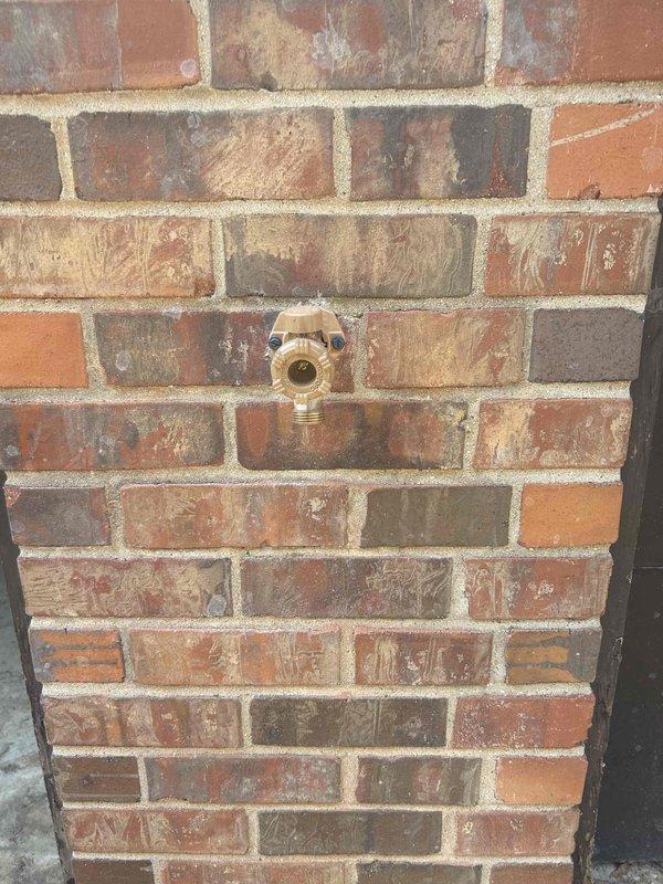 Responded to reported leak at outdoor hose bib that only occurred when water was turned on. Upon inspection, identified active leak in copper supply line approximately one inch upstream from exterior spigot, with visible water seepage on bottom side of horizontal copper pipe within wall cavity. Accessed interior plumbing through basement, located compromised section of copper piping at shutoff valve connection. Repaired leaking copper pipe joint and pressure tested system to verify complete seal. Confirmed no leakage during operation and restored full water flow to exterior spigot.