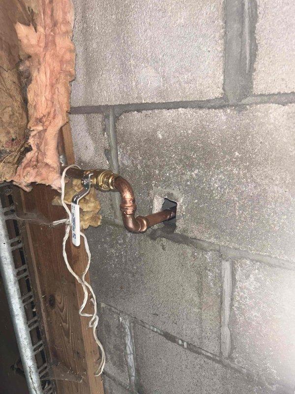 Responded to reported leak at outdoor hose bib that only occurred when water was turned on. Upon inspection, identified active leak in copper supply line approximately one inch upstream from exterior spigot, with visible water seepage on bottom side of horizontal copper pipe within wall cavity. Accessed interior plumbing through basement, located compromised section of copper piping at shutoff valve connection. Repaired leaking copper pipe joint and pressure tested system to verify complete seal. Confirmed no leakage during operation and restored full water flow to exterior spigot.