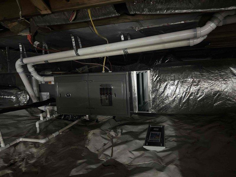 Completed comprehensive HVAC maintenance inspection on dual fuel system located in crawlspace environment. Performed thorough evaluation of air handler unit, verified proper operation of condensate drainage system with PVC piping configuration, and inspected insulated flexible ductwork connections on both supply and return sides. All components found operating within normal parameters, with equipment properly secured to floor joists and adequate clearances maintained for service access.
