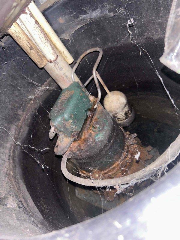 Performed comprehensive sump pump inspection and cleaning service for BNI referral member. Upon arrival, found pump assembly exhibiting severe corrosion with heavy rust accumulation on pump body, float switch mechanism, and associated hardware components. De-energized system and disconnected unit from discharge piping, then removed pump from basin for thorough cleaning. Utilized wire brush and water to remove dirt, debris, and corrosion from intake screen and exterior surfaces. Cleaned float assembly and removed accumulated sediment from sump pit interior. Reassembled system, restored all connections, and performed operational testing to verify proper pump activation and discharge function. Documented equipment condition with photographs showing extent of corrosion and deterioration throughout assembly.