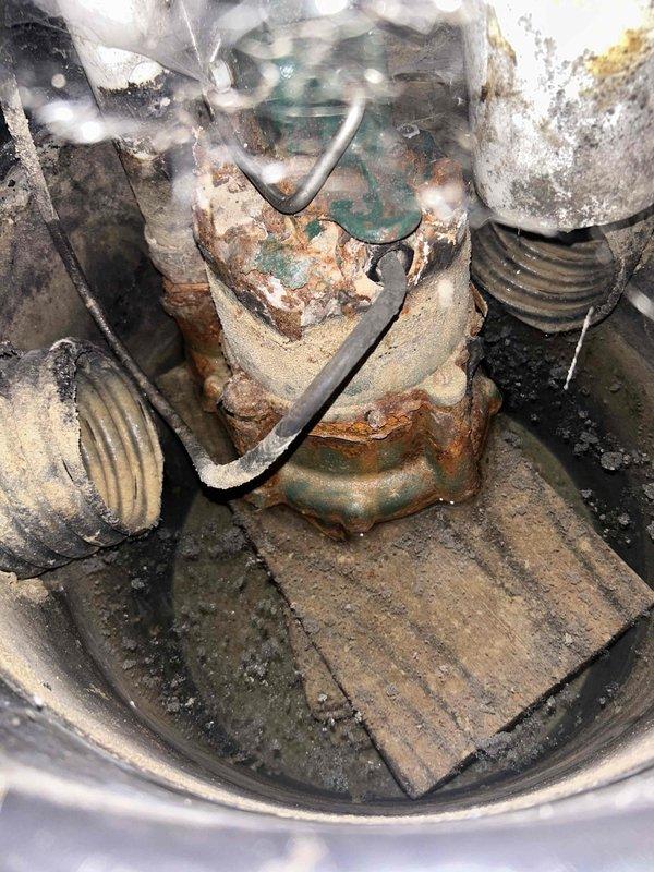 Performed comprehensive sump pump inspection and cleaning service for BNI referral member. Upon arrival, found pump assembly exhibiting severe corrosion with heavy rust accumulation on pump body, float switch mechanism, and associated hardware components. De-energized system and disconnected unit from discharge piping, then removed pump from basin for thorough cleaning. Utilized wire brush and water to remove dirt, debris, and corrosion from intake screen and exterior surfaces. Cleaned float assembly and removed accumulated sediment from sump pit interior. Reassembled system, restored all connections, and performed operational testing to verify proper pump activation and discharge function. Documented equipment condition with photographs showing extent of corrosion and deterioration throughout assembly.