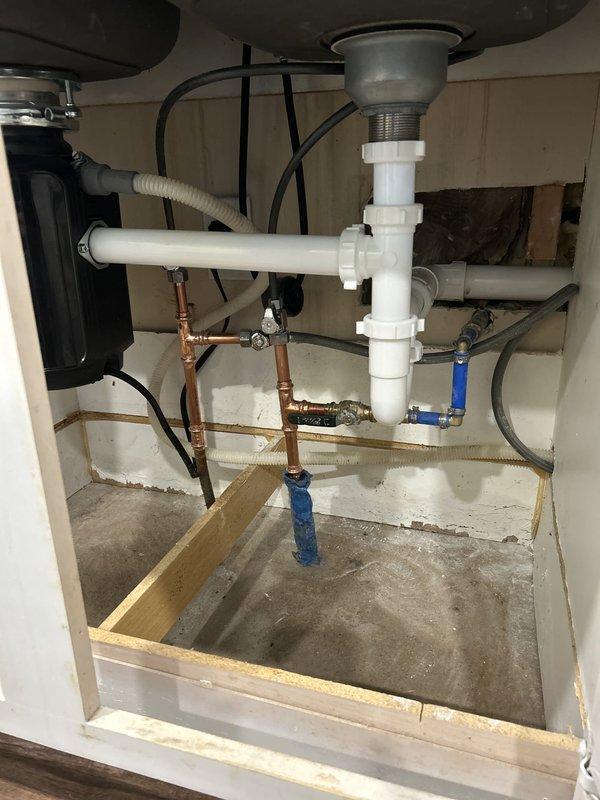 Completed comprehensive kitchen sink plumbing upgrade including replacement of existing drain trap and discharge assembly with new PVC piping in proper P-trap configuration while maintaining existing garbage disposal unit. Removed old water supply lines and installed new copper supply piping with soldered connections and new shutoff valves for both hot and cold water lines. Successfully installed customer-supplied brushed nickel pull-down kitchen faucet with high arched spout on double-basin stainless steel sink. All connections tested and verified leak-free, with proper water flow and drainage confirmed upon completion.
