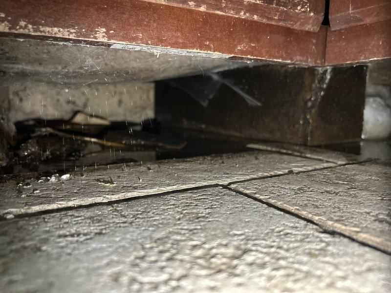 Responded to water leak complaint originating from kitchen sink area. Upon investigation, discovered active water intrusion in crawl space above kitchen with visible water droplets falling onto wooden subflooring. Traced leak source to compromised plumbing connection serving kitchen sink. Identified severe water damage to wooden cabinet base and subflooring materials beneath kitchen sink cabinet, including deteriorated wood with significant structural compromise and damaged substrate materials. Repaired faulty plumbing connection, stopped active leak, and verified system integrity. Documented extensive water damage to cabinetry and flooring for insurance purposes. Recommended immediate remediation of water-damaged materials to prevent mold growth and further structural deterioration.
