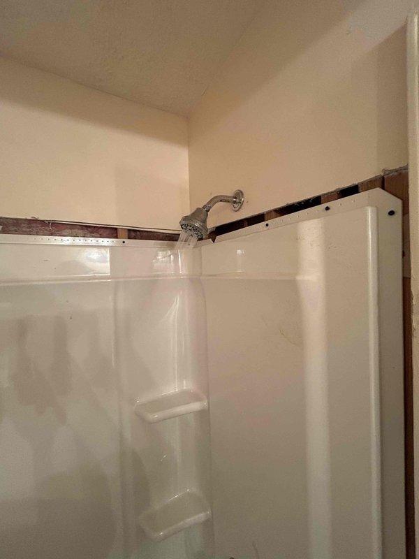 Completed installation of 30x60 right-hand white fiberglass tub/shower unit on first floor of vacant property. Removed existing tile and knockdown walls, then installed new knockdown wall panels around the unit without overlaying existing materials. Installed new shower valve assembly with Delta chrome trim body faucets, Delta chrome tub spout, and chrome showerhead on curved arm. Connected Watco waste and overflow assembly to drainage system and completed all necessary water supply and drain hookups to the new fixture. Verified proper water flow and drainage function, then cleaned and cleared work area of debris upon completion.