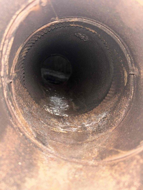 Returned to property to investigate oil furnace exhaust issue causing odors and eye irritation. Removed exhaust pipe and performed detailed inspection of chimney using camera equipment. Camera inspection revealed heavy accumulation of soot, combustion residue, and debris throughout the exhaust flue, confirming inadequate draft and blockage concerns identified during previous visit. The interior surfaces showed significant carbon buildup, corrosion, and sediment accumulation that was restricting proper exhaust ventilation and causing combustion byproducts to back up into the living space. Documented conditions with photographic evidence showing the extent of contamination within the flue system.