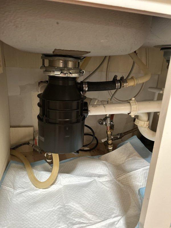 Responded to service call for non-operational garbage disposal unit with no humming noise. Upon inspection, found 5-year-old 1.3 horsepower disposal unit completely unresponsive, indicating electrical failure or motor seizure. Removed and replaced defective garbage disposal unit with new assembly, reconnecting all drain lines, dishwasher discharge hose, and electrical supply. Verified proper P-trap configuration, tested all connections for leaks, and confirmed new unit operates correctly with full grinding capability.