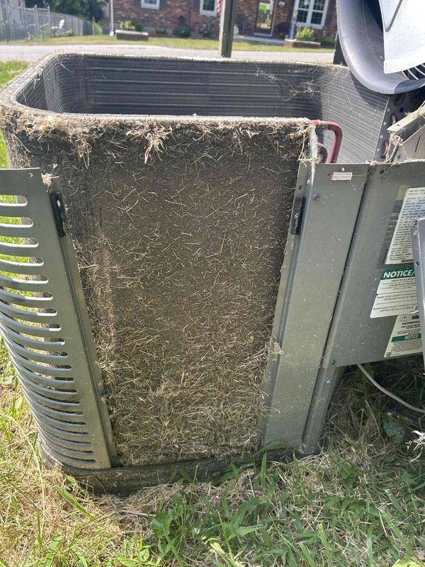 Responded to no cooling complaint on 4-year-old electric HVAC system with indoor temperature reading 87°F against thermostat setpoint of 80°F. Upon inspection, discovered outdoor condenser unit with severely restricted airflow due to extensive debris accumulation on condenser coil and protective grilles. Filter screens were completely obstructed with matted grass clippings, dirt, dust, and organic material buildup, preventing proper heat exchange and causing system to run continuously without adequate cooling capacity. Removed access panels and extracted heavy layer of compacted debris from condenser coil fins and surrounding protective screens. Cleaned condenser coil thoroughly to restore airflow and heat transfer efficiency. Inspected fan motor operation and verified proper rotation. Noted indoor air filter in crawlspace location had not been changed since system installation in May 2022, contributing to overall system inefficiency. Recommended immediate replacement of 16x20x4 indoor